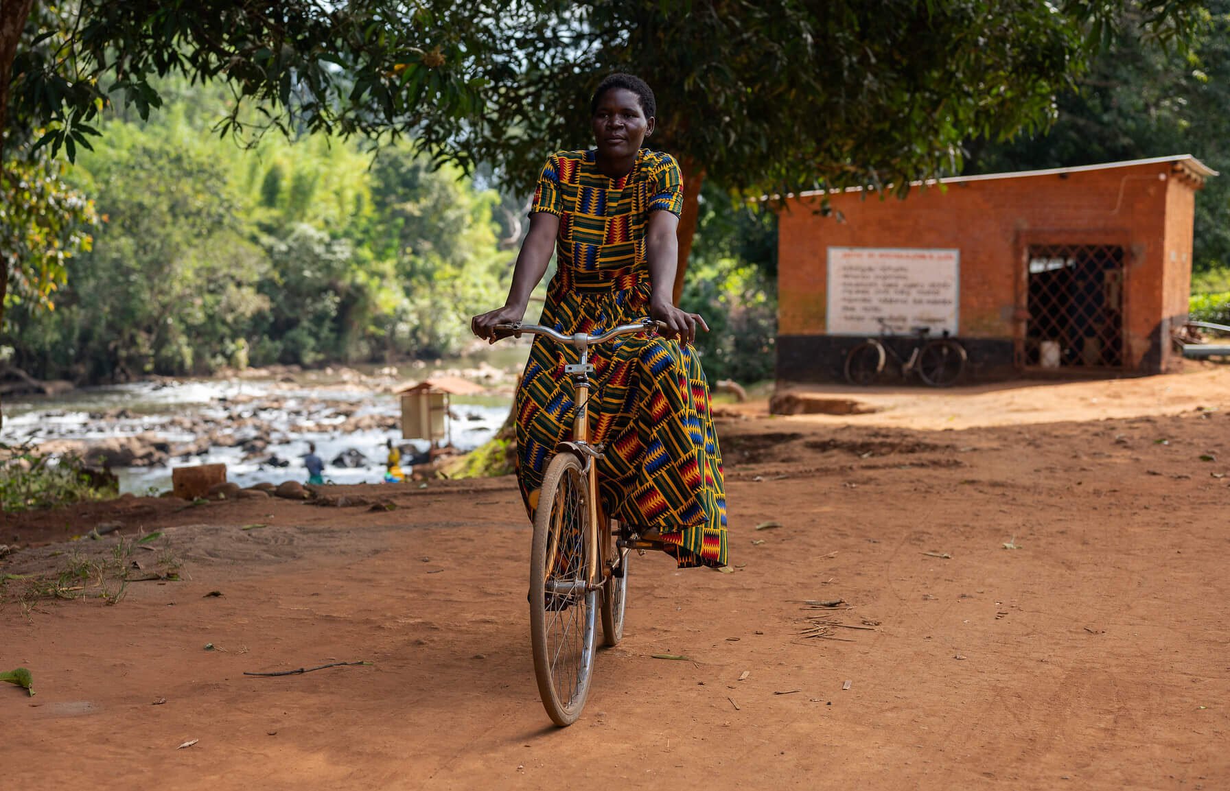 Eliza Bangula riding her bicycle which she bought after saving money for six months with the Amayi Otsogola VSLA. Taking part in the Ulalo programme and saving money gave Eliza an alternative to borrowing money from loan sharks at high rates of interest. Mulanje District, Malawi. Image: ETP/Homeline Media