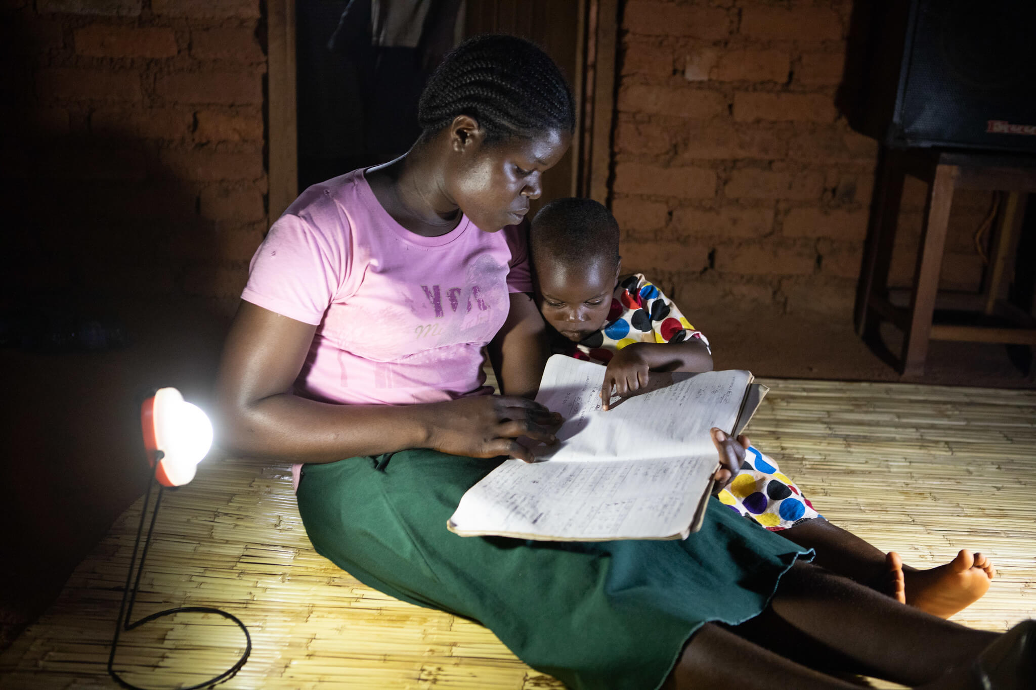 Beno Winesi and her daughter read by a solar lamp provided by the Kuwala initiative. Thyolo District, Malawi. Image: ETP.