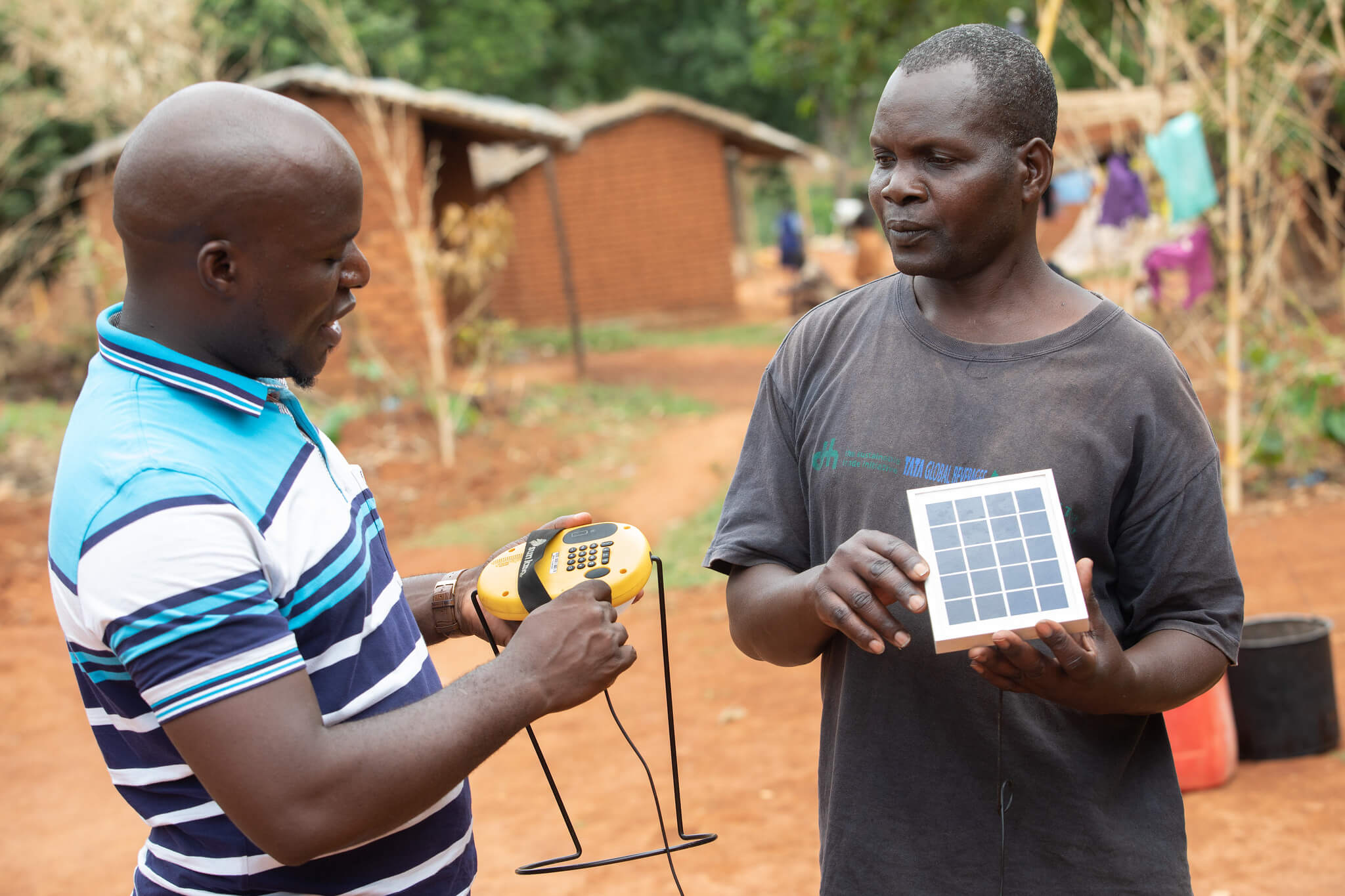 Mavuto Banda explains the workings of a solar lamp, provided by the Kuwala initiative, to Beno Winesi. Mulanje District, Malawi. Image: ETP